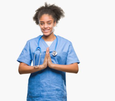 İzole arka plan birlikte AF emin gülümseyen için soran ellerle dua genç afro Amerikalı doktor kadın.