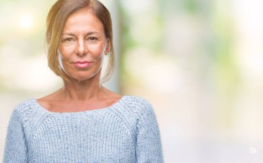 Yüzünde ciddi bir ifade ile izole arka plan üzerinde kış kazak giyen orta yaş üst düzey İspanyol kadın. Basit ve doğal kameraya bakıyor.