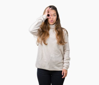 Sürpriz yüz, göz parmaklarının arasından seyir ile ok jest yapıyor izole arka plan üzerinde boğazlı kazak giyen genç güzel esmer kadın şok. İmansız ifade.