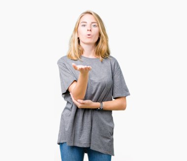 Bir öpücük el ile güzel ve seksi olmak hava üfleme kamera bakarak izole arka plan üzerinde büyük boy rahat t-shirt giyen güzel ve genç birbayan. Aşk ifade.