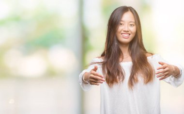 Sarılmak için kollarını açarak gülümseyerek kameraya bakarak izole arka plan üzerinde Genç Asyalı kadın. Neşeli ifade kucaklayan mutluluk.