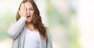 Artı boyutu genç kadın güzel üzerinde kış ceket giyen bir göz ile yüz ve sürpriz duygu kendinden emin gülümseme ile el kapsayan arka plan izole.