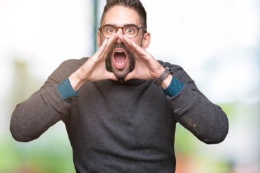 Kızgın ile yüksek sesle bağırarak izole arka plan üzerinde gözlük takan genç yakışıklı adam ağzına eller