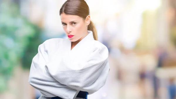 Young beautiful woman wearing karate kimono uniform over isolated background skeptic and nervous, disapproving expression on face with crossed arms. Negative person.