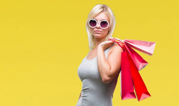 考えて深刻なスマートの顔に自信を持って式に分離された背景の上販売開催ショッピング バッグをショッピング若い美しいブロンドの女性 — ストック写真