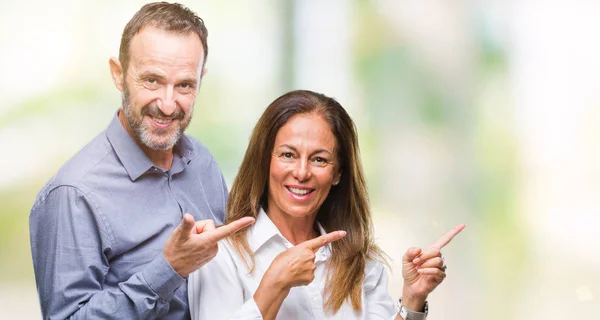 中年西班牙商业夫妇在孤立的背景微笑着 看着相机指向镜头 用两只手和手指指着一边 — 图库照片