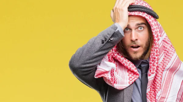 Young handsome arabian man with long hair wearing keffiyeh over isolated background surprised with hand on head for mistake, remember error. Forgot, bad memory concept.