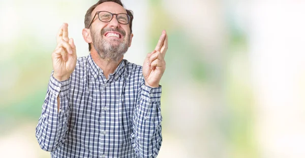 ハンサムな中年エレガントなシニア ビジネス男が眼鏡をかけて笑顔希望と目を閉じて交差指分離の背景の上 運と迷信的な概念 — ストック写真