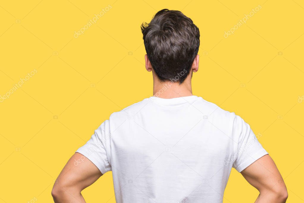 Young handsome man wearing white t-shirt over isolated background standing backwards looking away with arms on body