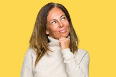 Üzerinde kış kazak giyen güzel orta yaş yetişkin kadın arka plan çene düşünme hakkında soru, dalgın ifade üzerine el ile izole. Düşünceli yüzüyle gülümsüyor. Şüphe kavramı.