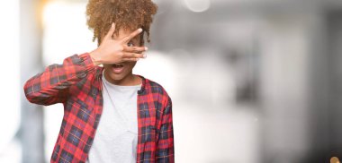 Mahcup ifadeyle parmaklarımın arasından yüz ve gözler el ile kapsayan şok bakmak izole arka plan üzerinde gözlük güzel genç Afro-Amerikan kadın arıyor.