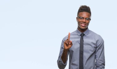 Genç Afro-Amerikalı iş adamı ve parmak gülümseyen süre bir numara ile kendinden emin ve mutlu yukarıyı gösteren izole arka plan üzerinde.