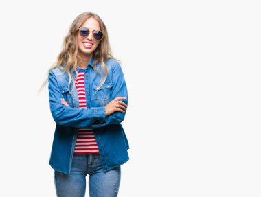 Güzel genç sarışın kadın üzerinde güneş gözlüğü takıyor mutlu yüz ile gülümseyerek kameraya seyir silah geçti arka plan izole. Olumlu bir kişi.