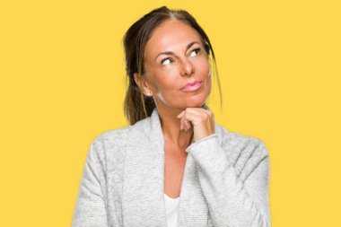 Üzerinde kış kazak giyen güzel orta yaş yetişkin kadın arka plan çene düşünme hakkında soru, dalgın ifade üzerine el ile izole. Düşünceli yüzüyle gülümsüyor. Şüphe kavramı.