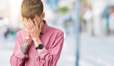 Yüzünü elleriyle ağlayarak süre kapsayan üzgün ifade ile izole arka plan üzerinde pembe gömlek giymiş yakışıklı delikanlı. Depresyon kavramı.