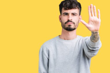Elin avuç durağı şarkı yapıyor izole arka plan üzerinde sweatshirt giyen genç yakışıklı adam. Negatif ve ciddi bir jest yüz ifadesiyle uyarı.