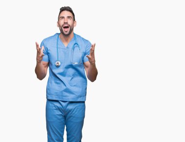 Yakışıklı genç doktor cerrah adam izole arka plan çılgın ve kızgın bağırarak ve agresif ifade ve silah kaldırdı bağırıyor. Hayal kırıklığı kavramı.