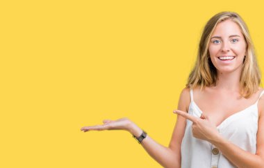 Hayret ve el ile sunulması ve parmak ile işaret ederken kameraya gülümseyen izole arka plan güzel genç kadın.