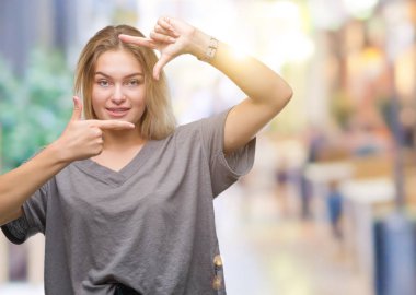 Elle yapma çerçeve ve parmakları ile mutlu yüz gülümseyen izole arka plan üzerinde beyaz kadın. Yaratıcılık ve Fotoğrafçılık kavramı.