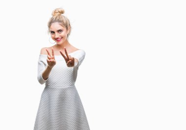 Genç güzel sarışın ve mavi gözlü kadın parmaklarını zafer işareti yaparken gösterilen kamera seyir gülümseyen izole arka plan yüzünden. İki numaralı.