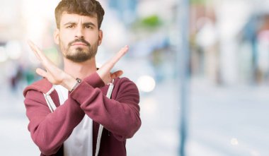 Genç yakışıklı adam izole arka plan ret ifade geçiş silah eksi işareti, kızgın surat yapıyor