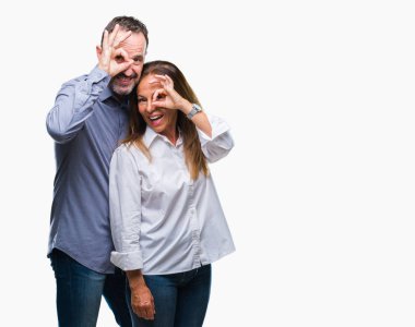 Orta yaş İspanyol iş çift el gülümseyen, ok jest yapıyor izole arka plan üzerinde göz parmakları ile mutlu yüz üzerinden seyir.