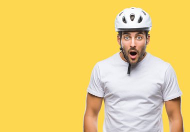 Yakışıklı delikanlı izole arka plan korkuyor ve şok sürpriz ifade, korku ve heyecan yüz üzerinden bisikletçi Güvenlik kask giyiyor.