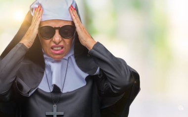 Orta yaş üst düzey Katolik Rahibe kadın güneş gözlüğü takmış çünkü umutsuz ve stresli baş ağrısı acı izole arka plan üzerinde ağrı ve migren. Ellerini kafasına.