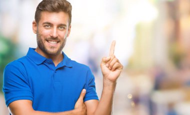 Kameraya bakarak yan el ve parmak ile işaret eden genç yakışıklı adam yüzünde kocaman bir gülümseme ile izole arka plan üzerinde.