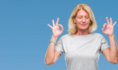 Orta yaş sarışın kadın izole arka plan üzerinde dinlenmek ve gülümseyen gözlerle parmak ile meditasyon jest yapıyor kapalı. Yoga kavramı.