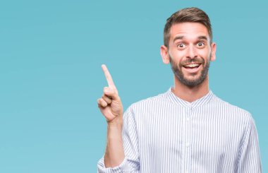 Kameraya bakarak yan el ve parmak ile işaret eden genç yakışıklı adam yüzünde kocaman bir gülümseme ile izole arka plan üzerinde.