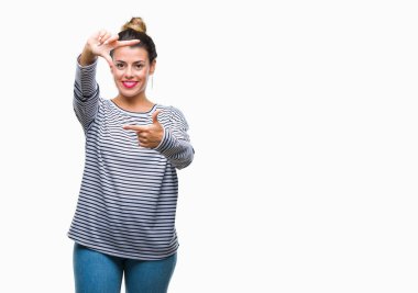 Genç güzel kadın rahat çizgili süveter elle yapma çerçeve ve parmakları ile mutlu yüz gülümseyen izole arka plan üzerinde. Yaratıcılık ve Fotoğrafçılık kavramı.