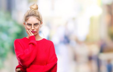 Kırmızı kazak ve gözlük seyir yorgun ve bıkkın ile depresyon sorun Çapraz kollar ile izole arka plan düşünme üzerinde giyen genç güzel sarışın kadın.