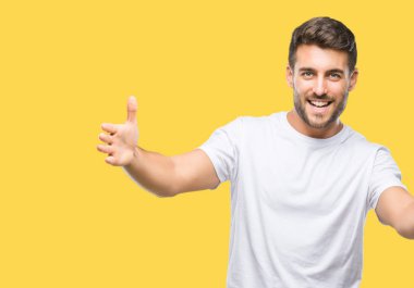 Yakışıklı delikanlı sarılmak için kollarını açarak gülümseyerek kameraya bakarak izole arka plan üzerinde. Neşeli ifade kucaklayan mutluluk.