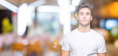 Üzerinde beyaz t-shirt giyen genç yakışıklı adam arka plan gevşek yüzünde ciddi bir ifade ile izole. Basit ve doğal kameraya bakıyor.