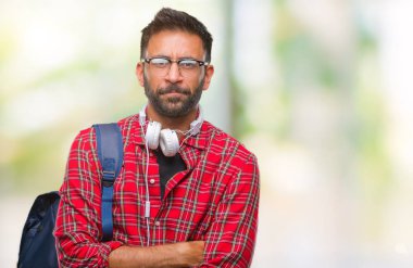 Yetişkin İspanyol öğrenci adam izole arka plan şüpheci ve sinir, onaylamayan ifade yüz çapraz kolları üzerinde kulaklık ve sırt çantası giyiyor. Negatif kişi.