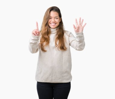 Gösterilen arka plan üzerinde boğazlı kazak giyen genç güzel esmer kadın izole ve parmakları ile işaret kendinden emin ve mutlu gülümseyerek süre 6 numara.