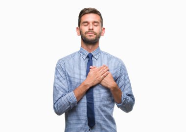 Genç yakışıklı iş adamı izole arka plan ile gülümseyen üzerinde kapalı gözler ve yüzünde minnettar jest ile göğüs üzerinde eller. Sağlık kavramı.