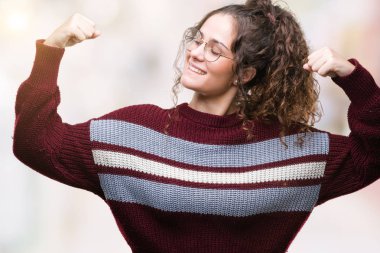 Güzel esmer kıvırcık saçlı Genç kız üzerinde gözlük takan gururlu gülümseyen kol kasları gösterilen arka plan izole. Fitness kavramı.