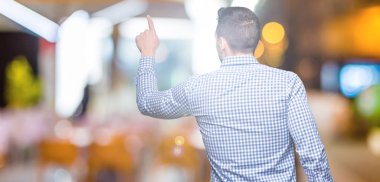 İzole genç yakışıklı adam arka plan geriye doğru arkasında parmak eliyle işaret Posing