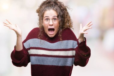 Güzel esmer kıvırcık saçlı Genç kız üzerinde gözlük takan deli kutluyor arka plan izole ve çığlık kaldırdı ve açık gözleri heyecanlı silah ile başarı için hayrete düşürdü. Kazanan kavramı