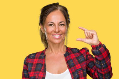 İzole arka plan gülümseyen ve boyutu işaret parmaklı ararken ve kamera işi el ile kendinden emin eller üzerinde rahat ceket giyen orta yaş yetişkin kadın. Ölçü kavramı.