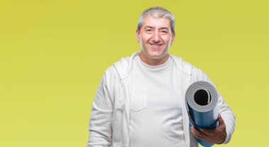 Üst düzey yakışıklı duran ve diş gösterilen kendine güvenen bir gülümsemeyle gülümseyerek mutlu bir yüz ile izole arka plan üzerinde yoga mat holding