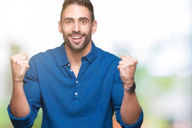 İzole arka plan kutlama üzerinde genç yakışıklı adam şaşırttı ve başarı için kaldırdı kollarını açarak hayret ve gözleri açık. Kazanan kavramı.