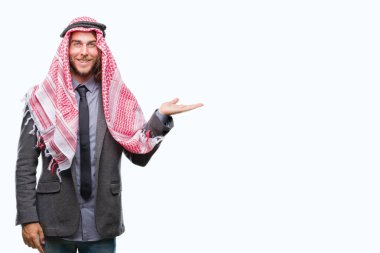 Uzun saçlı keffiyeh neşeli sunulması ve kameraya bakarak avucunun ile işaret gülümseyen izole arka plan üzerinde giyen genç Arap yakışıklı.
