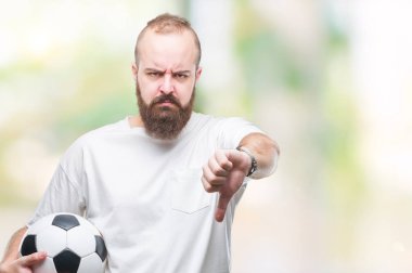 Kızgın yüz, eksi işareti aşağı antipati başparmak ile gösterilen, ret kavramı ile izole arka plan üzerinde futbol futbol topu tutan genç beyaz hipster adam