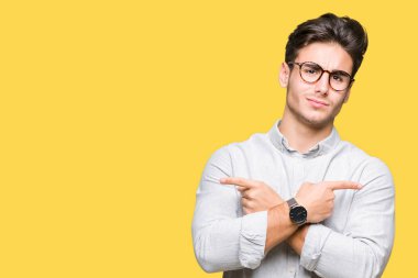 Genç yakışıklı adam gözlük izole üzerinde işaretleme için her iki parmak, farklı yönde ile katılmıyorum arka plan