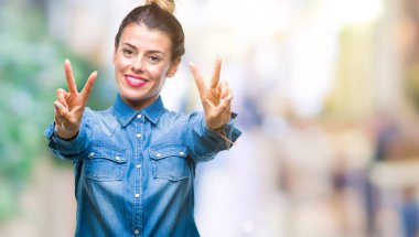 Genç güzel kadın parmaklarını zafer işareti yaparken gösterilen kamera seyir gülümseyen izole arka plan yüzünden. İki numaralı.