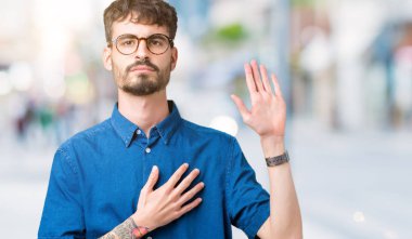 Yakışıklı delikanlı gözlüklü üzerinde arka izole göğüs ve bir sadakat sözü yemin yapma avuç, el ile küfür