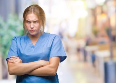 İzole arka plan şüpheci ve sinir, onaylamayan ifade yüz çapraz kolları olan cerrah üniforma giyen genç beyaz hemşire kadın. Negatif kişi.